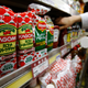 Kagome's tomato ketchup bottles are displayed with their price tag as a staff arranges tomato ketchup bottles of other brands at Yoshiike supermarket in Tokyo